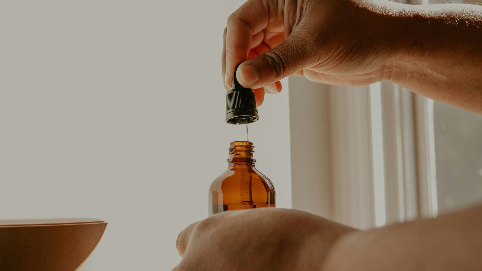 CBD dosage guide — hand holding amber dropper bottle in natural light