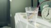 CBD vs melatonin — glass of water and alarm clock on bedside table