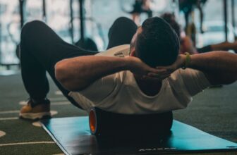 A person lying on a mat foam-rolling their upper back at the gym — active muscle recovery after exercise.