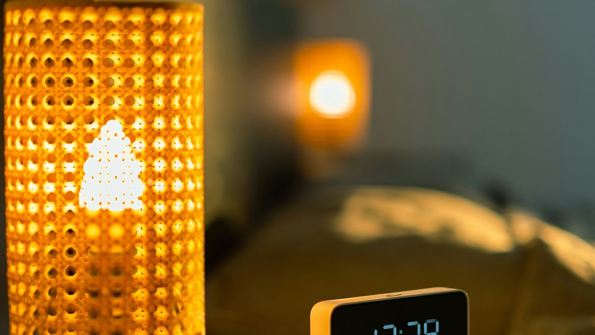 A warm bedside lamp glowing softly in a dark bedroom at night.