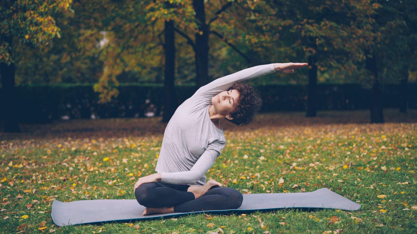 A person doing a gentle seated side stretch outdoors on the grass