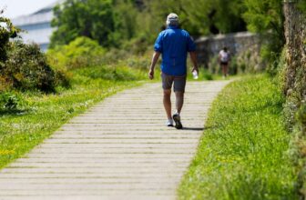 A person walking uphill on a green paved path