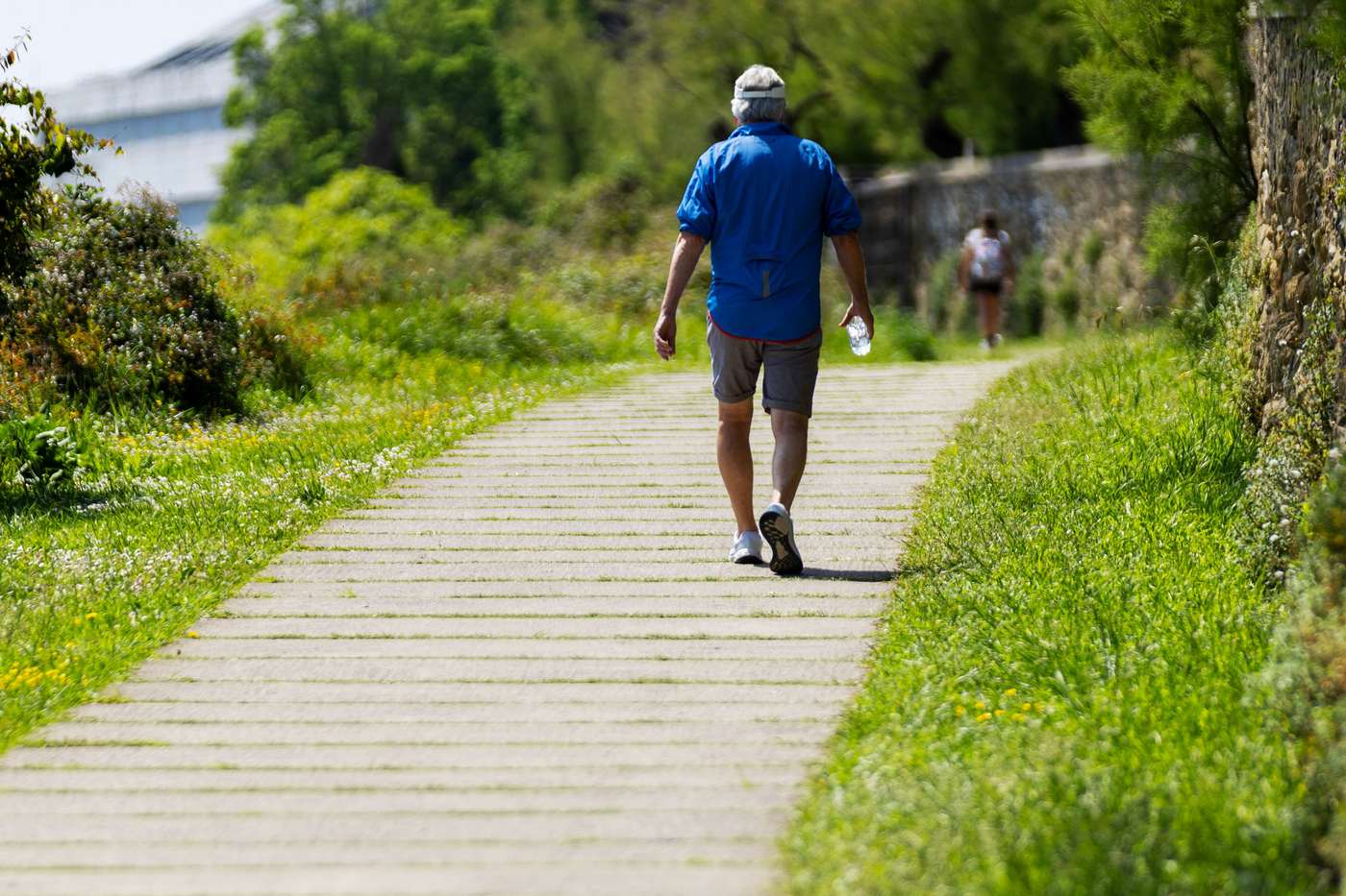 A person walking uphill on a green paved path