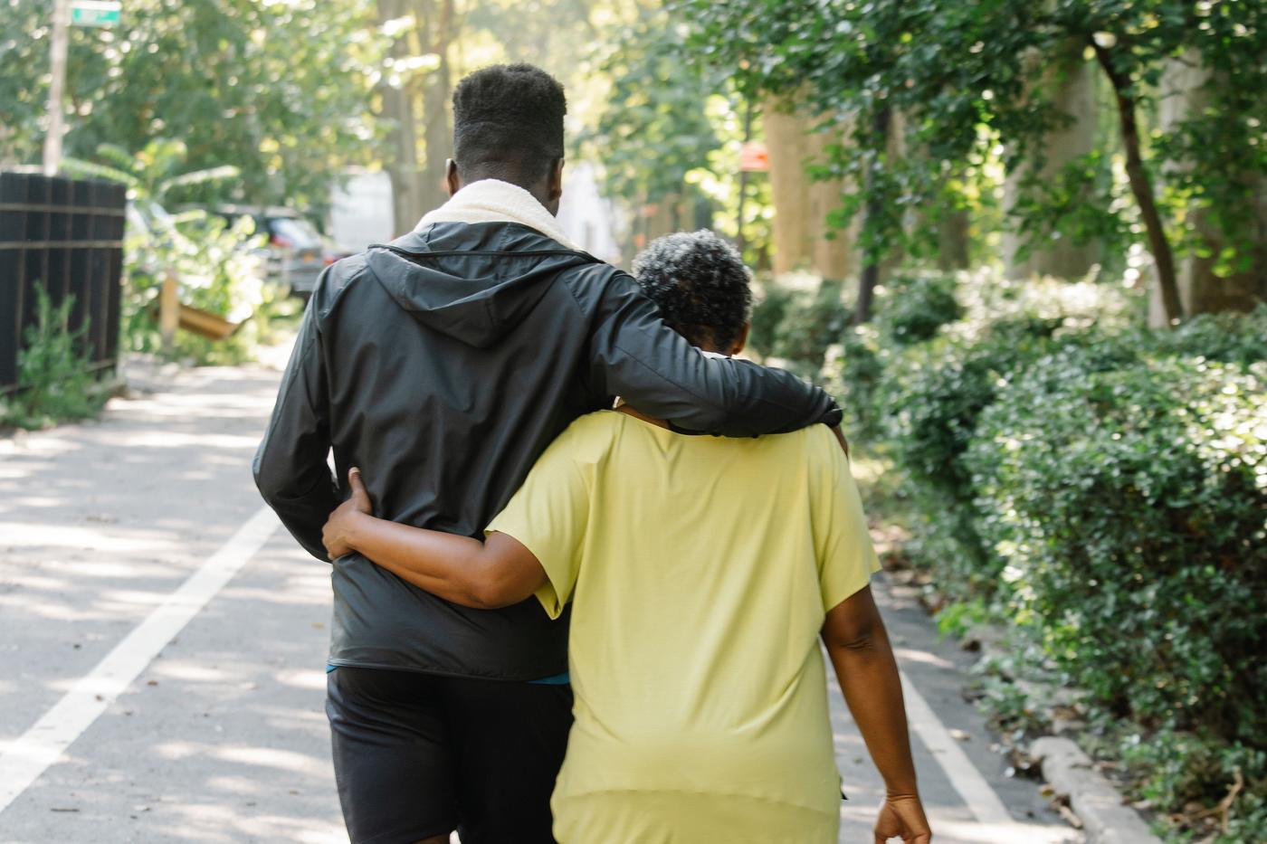Two men walking together outdoors, one with an arm around the other