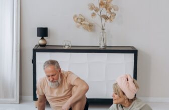 Two older adults stretching on the floor of a living room