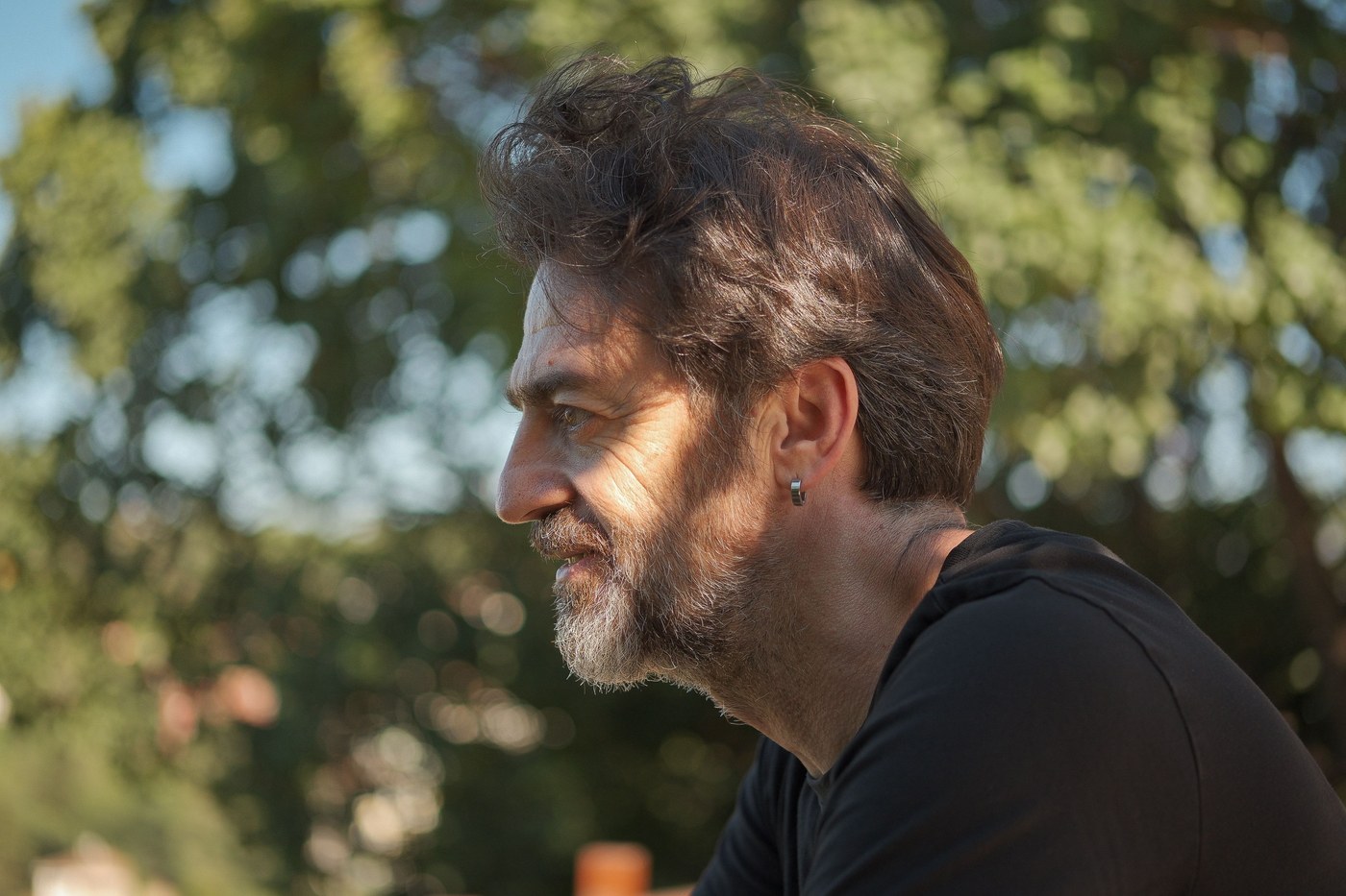 A middle-aged man sitting outdoors in warm afternoon light